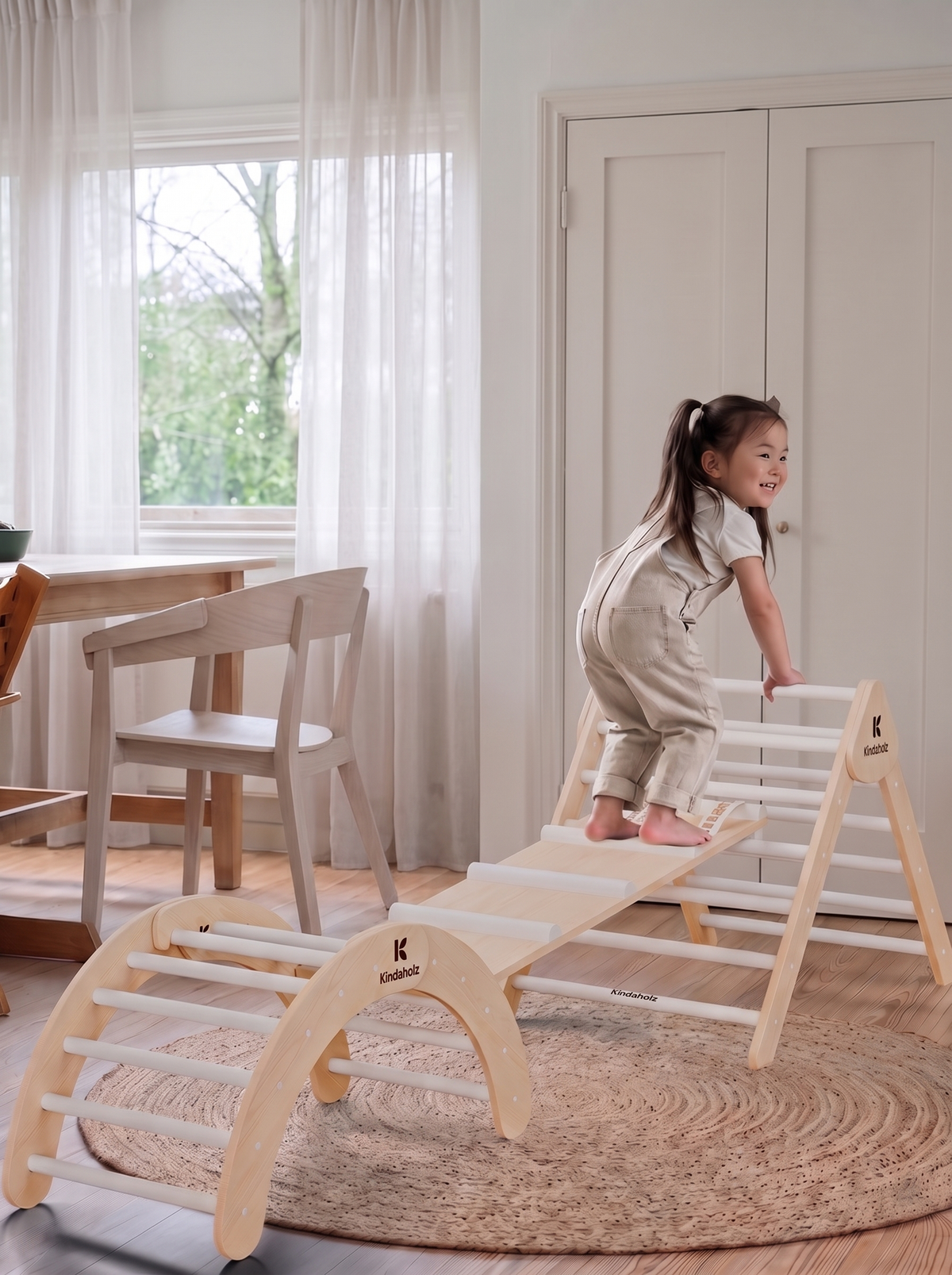 Kind klettert im Wohnzimmer auf das Kletterset aus Kletterdreieck, Rutsche und Kletterbogen